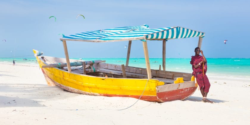 Man leans on boat on Paje Beach.