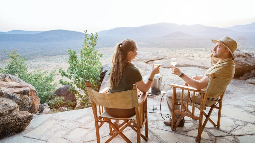 Couple on honeymoon enjoying a drink and the view from a luxury safari lodge in Kenya.