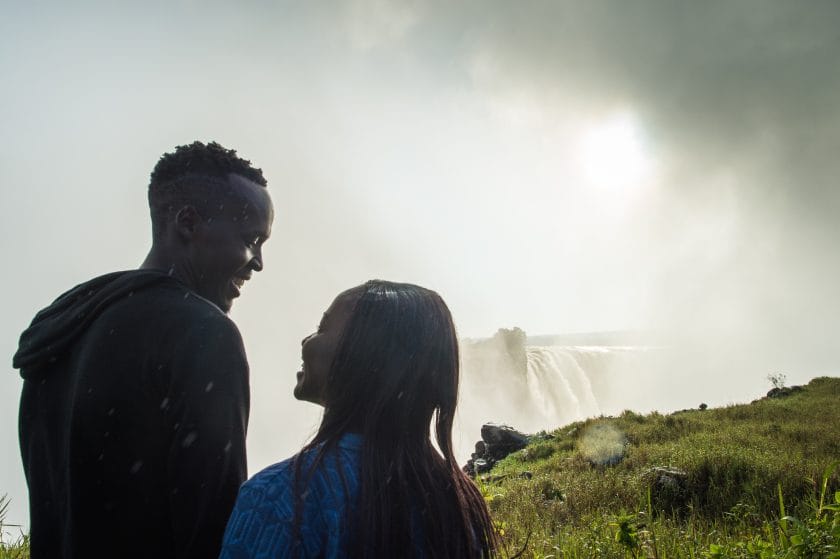 A happy couple standing in the Victoria Falls mist